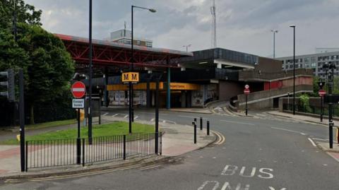 An external view of Regent Centre station. A yellow Tyne and Wear Metro sign indicates the station.