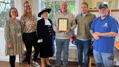 Andy Watson (centre) gets his award from the High Sheriff of Kent