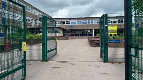 Green gates and a 1960s style school building in the background