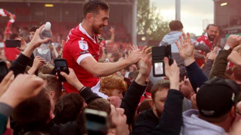 Jack Marriott of Wrexham on the shoulders of fans at the full time whistle as Wrexham players celebrate promotion to the Championship