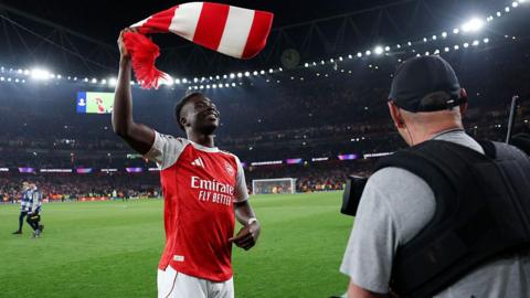 Bukayo Saka of Arsenal waves a scarf as he celebrates victory