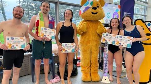 Two male and three females in swimming gear and holding certificates with Children in Need's Pudsey.