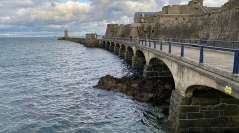 The breakwater bridge at Castel Cornet with the sea on the left.