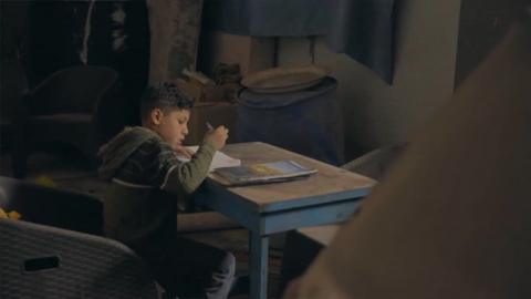 boy doing homework at desk.