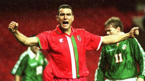 Vinnie Jones with arms out wide and shouting in Wales kit