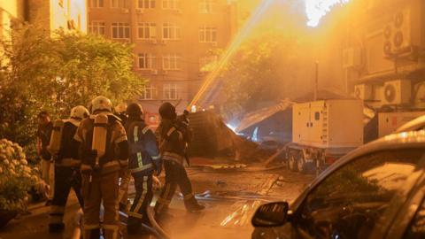 An explosion is seen after a Russian drone strikes a building as Ukrainian firefighters battle a fire in another building previously hit by a drone during a Russian air attack on Kyiv,