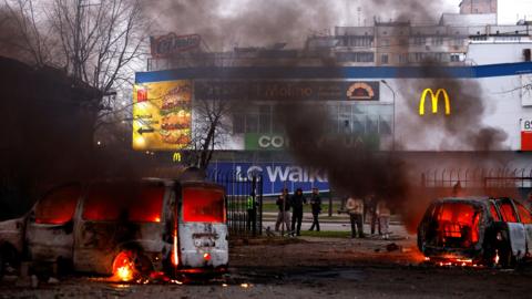 Smoke rises from two burnt-out cars in front of a shopping centre in Kyiv.