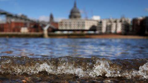 Small wave on River Thames in foreground with St Paul's out of focus in background