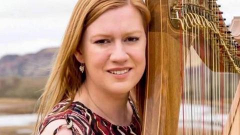 Jennifer Port has blonde hair and is pictured outdoors with her clarsach, a traditional Celtic harp.
