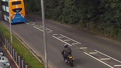 A motorcyclist on a road behind a bus