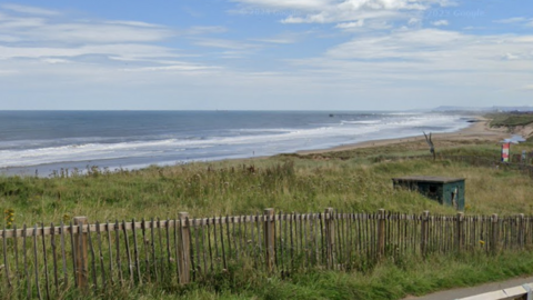 Sea waves sweep Crimdon Dene beach, which is surrounded by fenced off grassland.