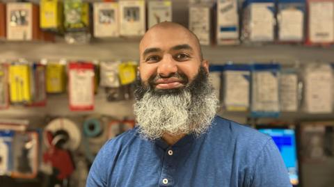 Abdul Ghafoor, an Asian man with a black and grey beard. He is smiling in the photo and wearing a blue t-shirt.