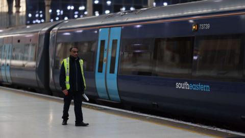  A worker walks alongside a blue Southeastern train at Victoria Station