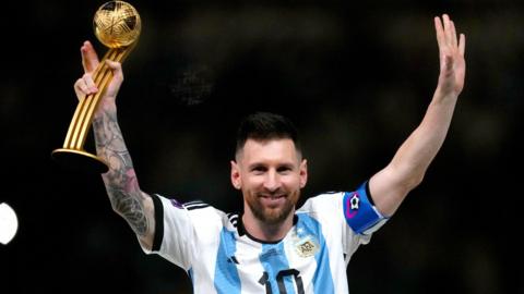 Argentina captain Lionel Messi raises his arms while holding a trophy