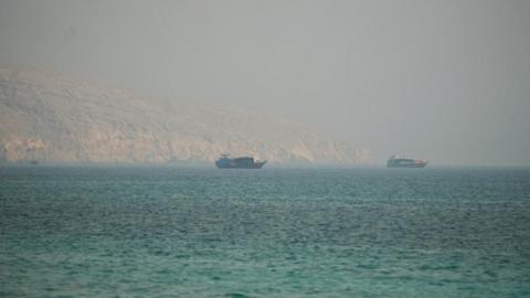 Two vessels are seen in the Strait of Hormuz, surrounded by rocky mountains, from Musandam, Oman