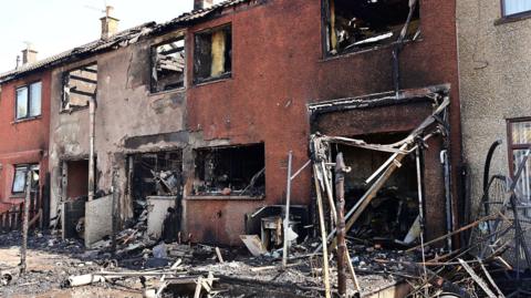 Row of white and red burnt out houses
