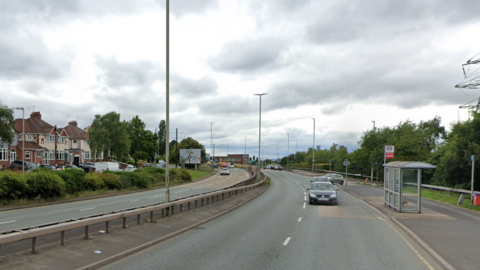 Image shows a dual carriageway, with houses on the left handside and cars travelling down the right hand side