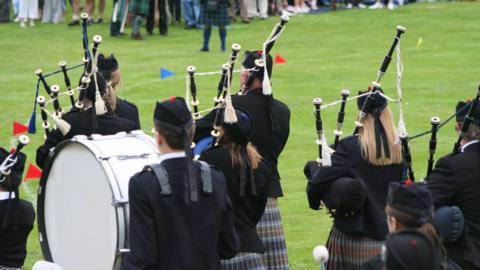 Generic image of pipe band playing in a field with people observing