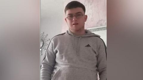 Daniel Ambler, a 23-year-old man with short dark hair, wearing spectacles and a grey hoodie.
