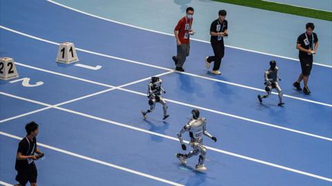 Humanoid robots run as they compete in the 100 metre demonstration event at the World Humanoid Robot Games