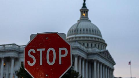 An image of a stop sign infront of the US Capitol 