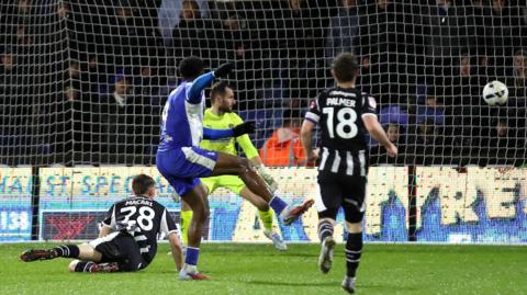 Mike Fondop holds his right leg in the air as the ball flies into the goal net