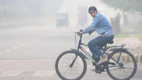 Girl on a bike in smoggy Delhi