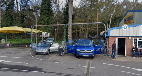 A general view of the Fiveways Car Wash near Barton Mills. Two vehicles are being cleaned as people wait on from the right hand side.