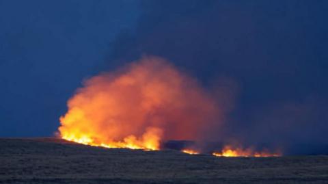 A night-time image of a large fire on Salisbury Plain against an inky blue sky in Wiltshire.