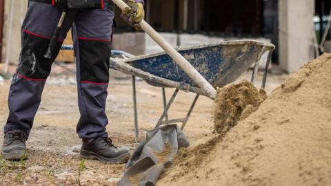 Builder shovelling sand