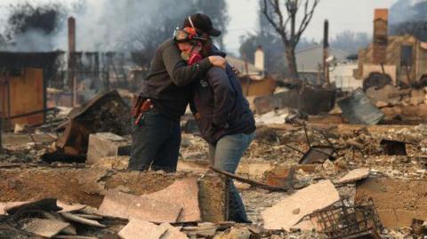 Two people embrace as they inspect a family member's property that was destroyed by the Los Angeles wildfires.