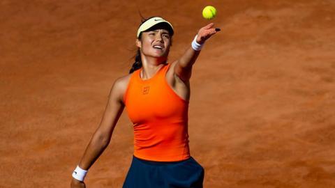Emma Raducanu serves on a clay court