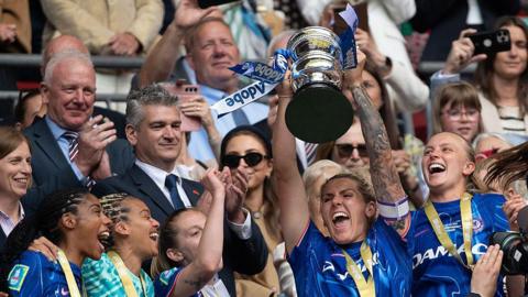 Millie Bright of Chelsea lifts the Women's FA Cup in the royal box at Wembley in May 2025.
