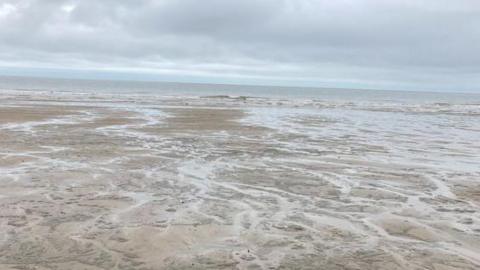 Sandy beach at Sutton on Sea with wavy sea in background