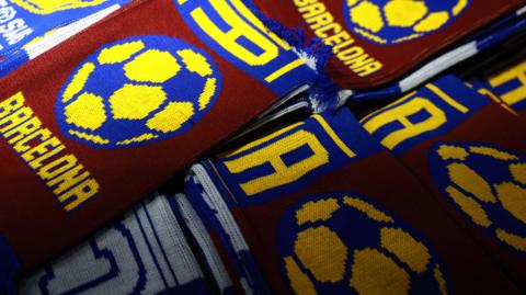 FC Barcelona maroon and blue scarves layered on top of a table at a stall outside a stadium.