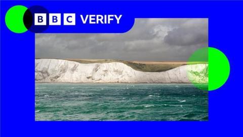 A photo of the white cliffs of Dover against a sky with grey clouds, with BBC Verify branding in bright blue and green around it.