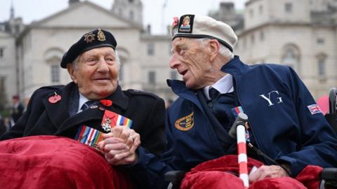 Two veterans hold hands ahead of Remembrance service in London