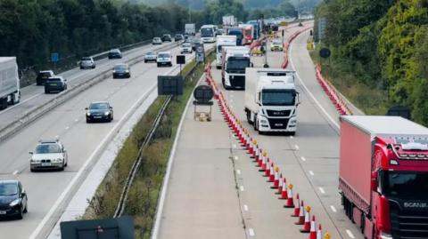Lorries heading to Dover queuing on one side of the M20, herded by long rows of traffic cones  