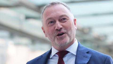 Environment secretary Steve Reed, wearing a red tie and suit, walks in to ý Broadcasting House in London, to appear on the ý One current affairs programme, Sunday with Laura Kuenssberg