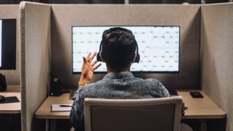 Llun o ddyn ar alwad mewn call centre
