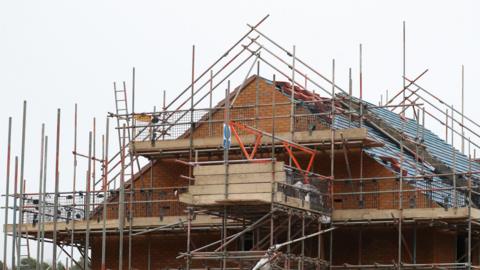 A house surrounded by scaffolding on a grey day.
