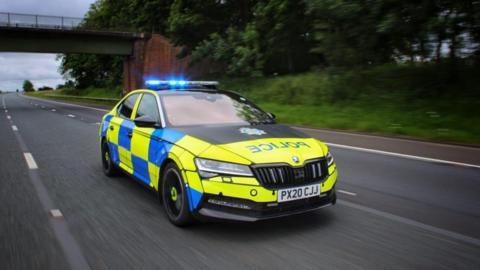 A generic picture of a Cumbria Police car driving along a motorway. The car has its blue lights on. It is driving at speed.