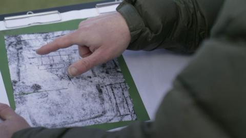 A finger pointing to the scan of an ancient Roman villa