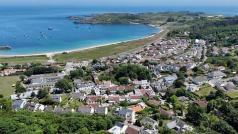An aerial view of homes in Alderney and the bay of Newtown. Blue seas.