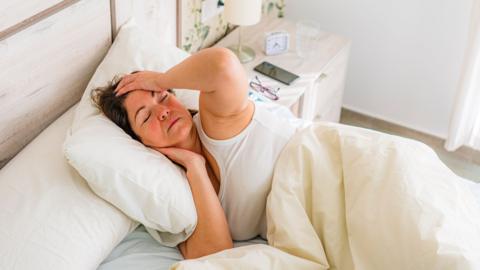 A woman looks hot in her bed