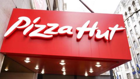 A bright red Pizza Hut logo on the side of a building 