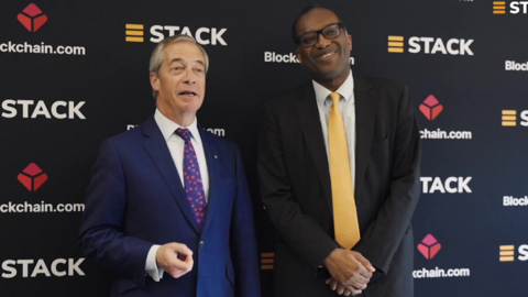 Reform UK leader Nigel Farage (L) stands with former Chancellor Kwasi Kwarteng (R) as they promote cryptocurrency. Farage wears a dark blue suit, a white shirt and a blue tie with red blossoms. Kwarteng wears a black suit, a white shirt and a butter yellow tie.