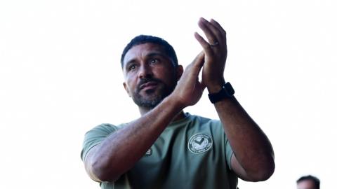 Newport County boss Hayden Mullins applauds supporters.