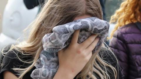 Woman holding blanket to her face outside court