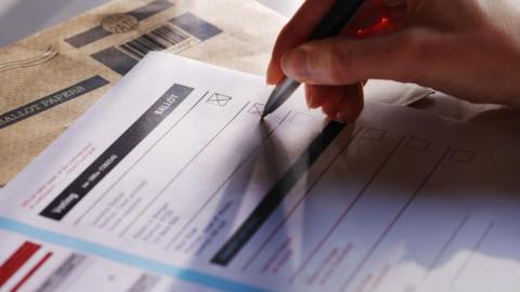 A ballot paper and a hand with a pen marking an X upon it